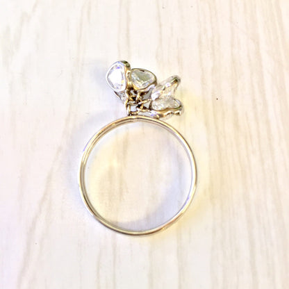 14 karat white gold ring with dangling heart charm adorned with sparkling cubic zirconia stones on a light wood background, perfect holiday gift idea for her.