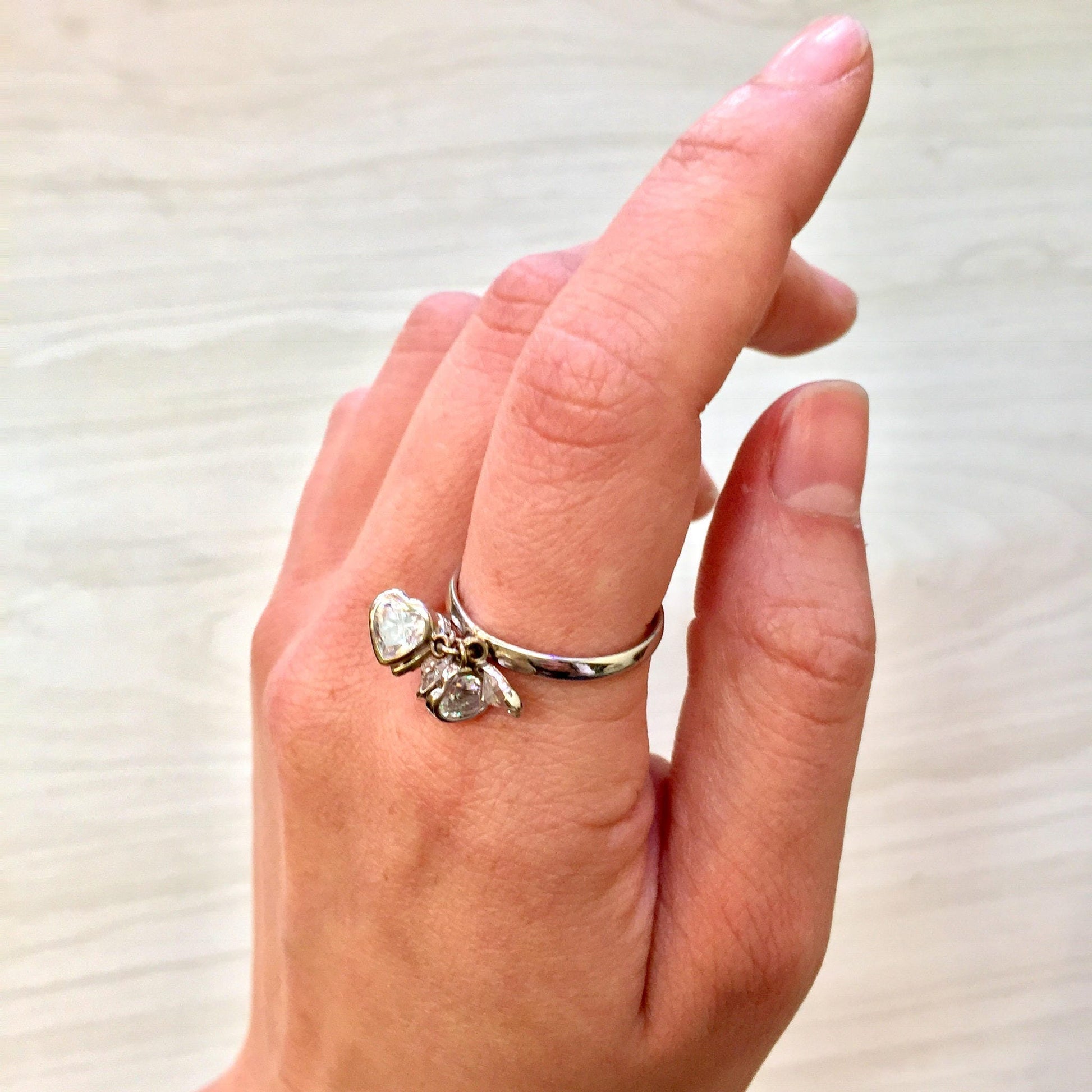 14K white gold heart-shaped ring with cubic zirconia stones on a person's hand, showing the ring from various angles against a light background.