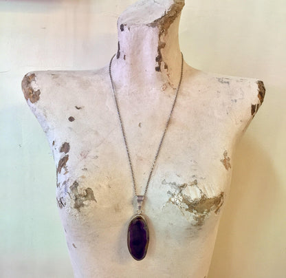 Vintage sterling silver purple agate pendant necklace on display, showcasing the large oval-shaped purple gemstone against an aged white mannequin bust.