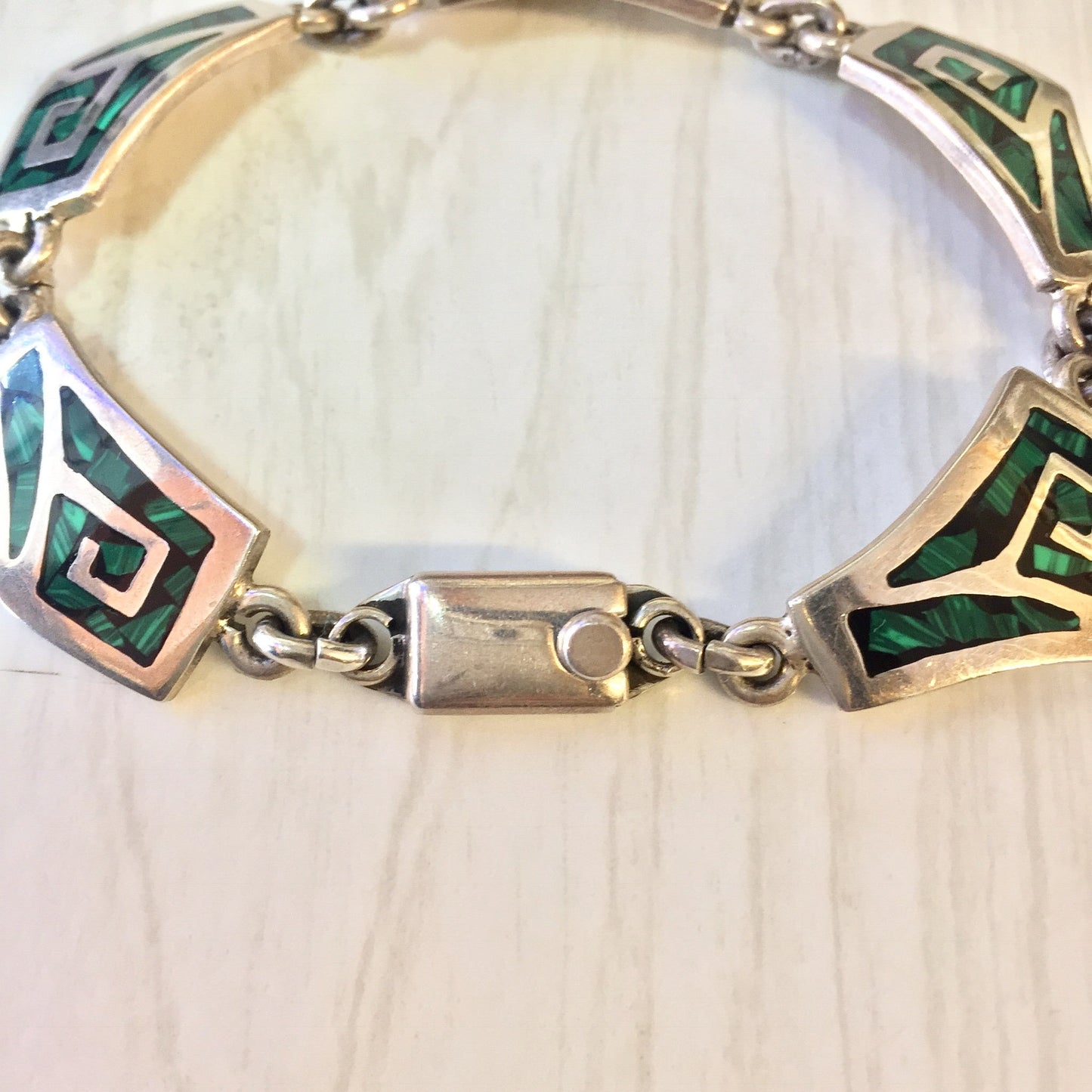 Vintage sterling silver link bracelet with green malachite inlay stones on a light wooden surface