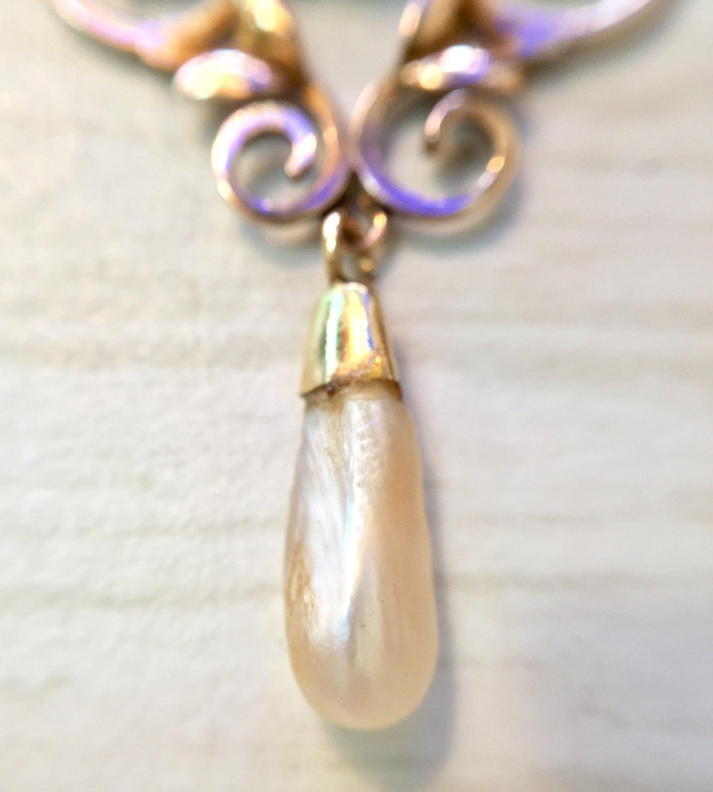 10K gold antique pendant necklace with fresh water pearl drop and swirling amethyst accents, showcasing intricate metalwork on delicate chain against soft fabric background.