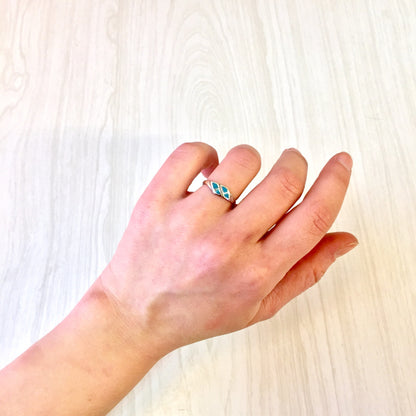 Vintage sterling silver ring with turquoise stone on a hand against a light wooden background