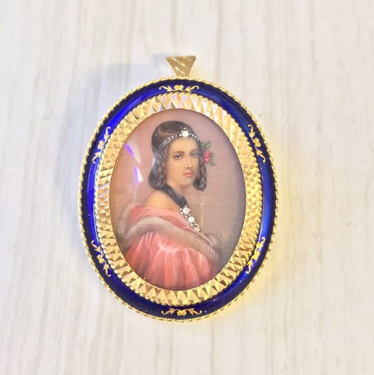 18 karat gold Victorian brooch pendant featuring a hand-painted portrait miniature of a woman in a pink dress, set in an ornate blue enamel frame accented with gold scrollwork and a diamond, can be worn as a brooch or pendant, antique jewelry piece from the Victorian era.