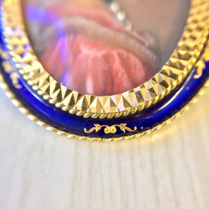 Antique 18 karat gold Victorian brooch pendant featuring a cameo, diamonds, and an intricate gold setting, shown in closeup on a wooden surface.