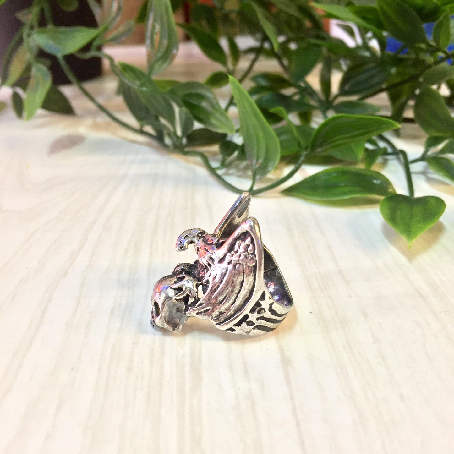 Vintage sterling silver statement ring featuring an eagle head with a skull, surrounded by leafy greenery, creating a bold biker jewelry style.