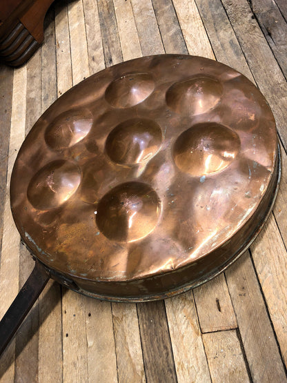 Antique copper pan with dimpled surface on rustic wooden table, vintage kitchenware for poaching eggs or country folk art home decor