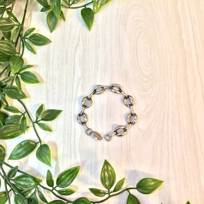 Vintage sterling silver link bracelet on wooden surface surrounded by green leaves