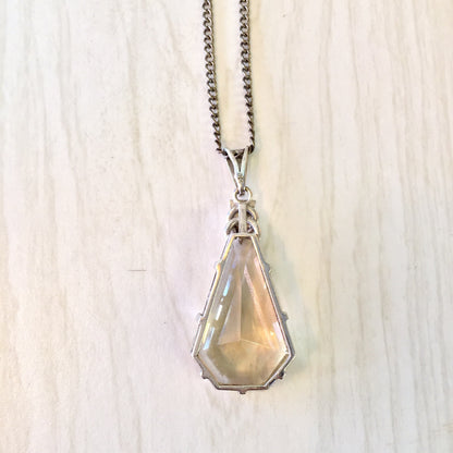 Smoky quartz pendant necklace in Art Deco style with long silver chain on light wood background