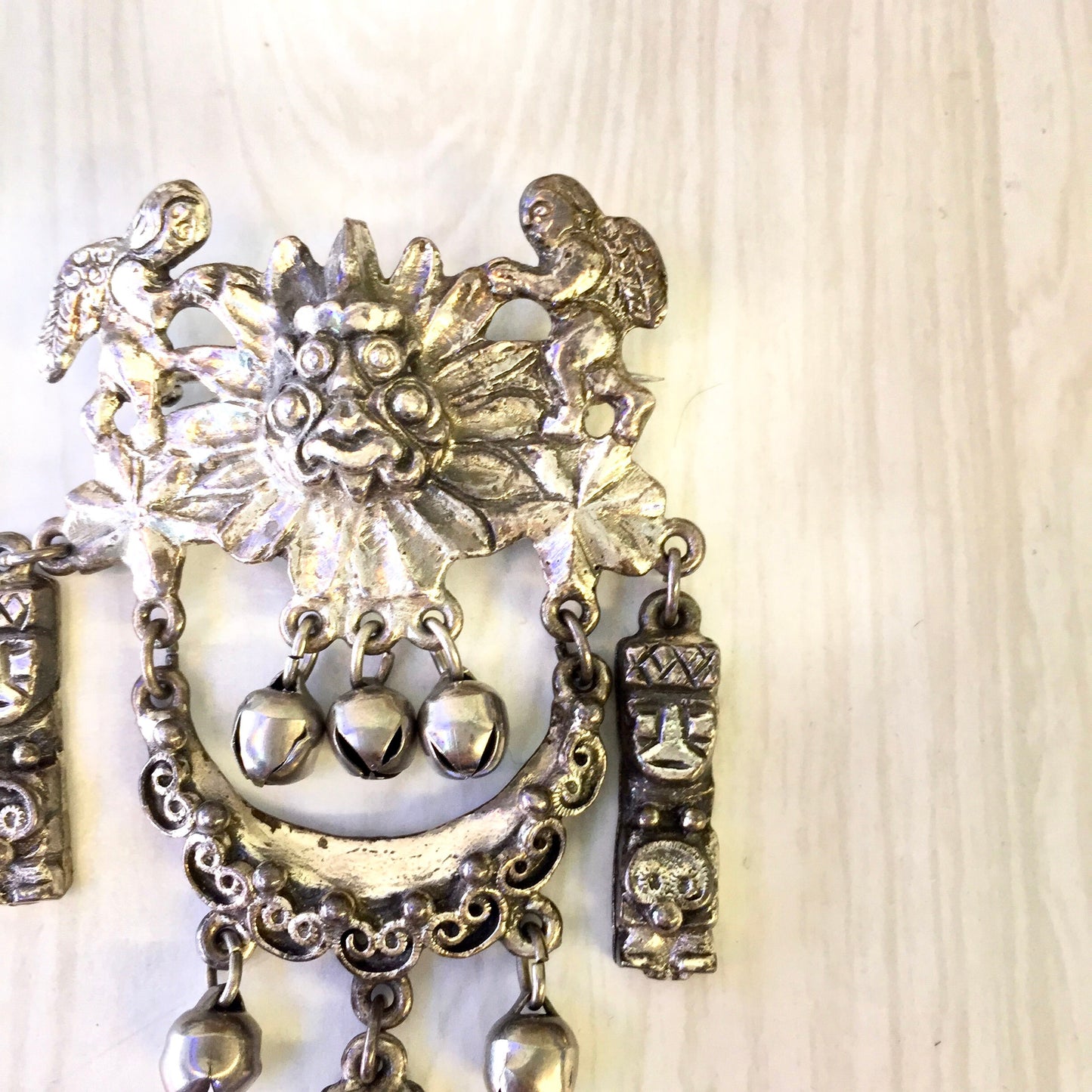 Vintage silver tone Peruvian art brooch featuring intricate filigree design with hanging bells and floral motif, a statement jewelry piece that can be worn as a pin or brooch, perfect as a gift or addition to any costume jewelry collection.