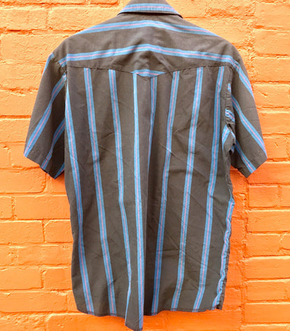 Vintage striped short sleeve button-down shirt hanging on brick wall