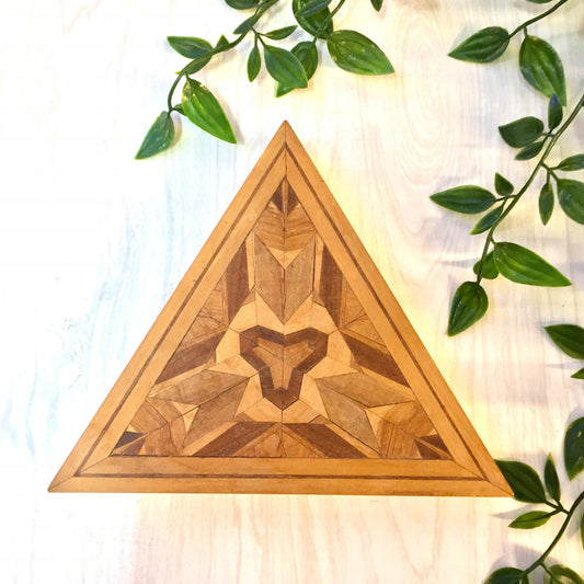 Vintage wooden triangle-shaped trinket box with intricate inlaid mosaic wood pattern, surrounded by green foliage, handmade decorative catch-all gift box
