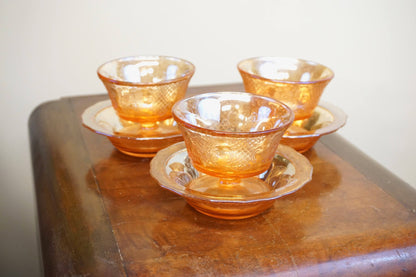 Set of three vintage iridescent orange carnival glass dessert dishes on wooden surface