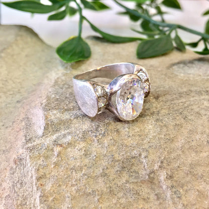 Vintage sterling silver statement ring with large oval cut diamond on textured stone background with greenery