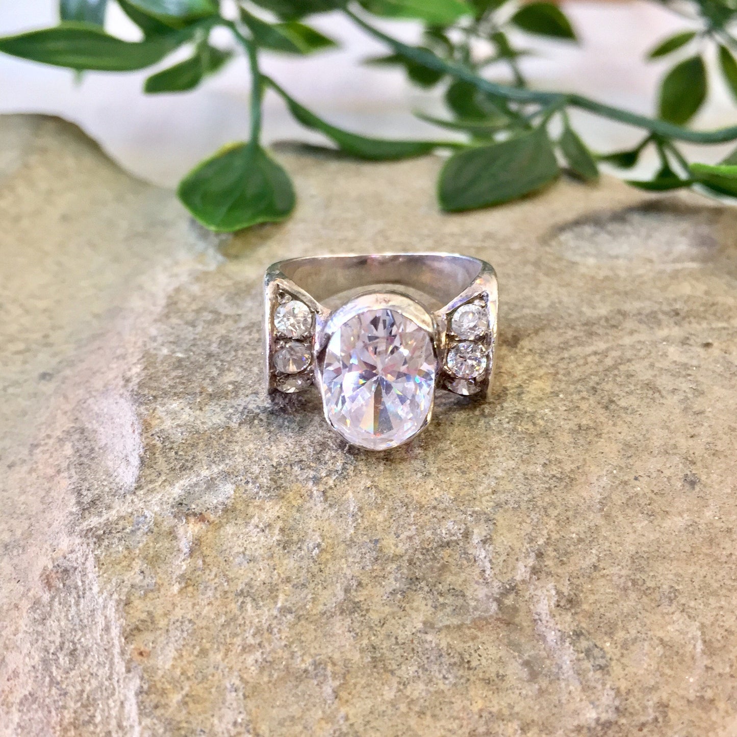 Vintage Sterling Silver Statement Ring with Oval Cut Diamond on Stone Background with Green Leaves