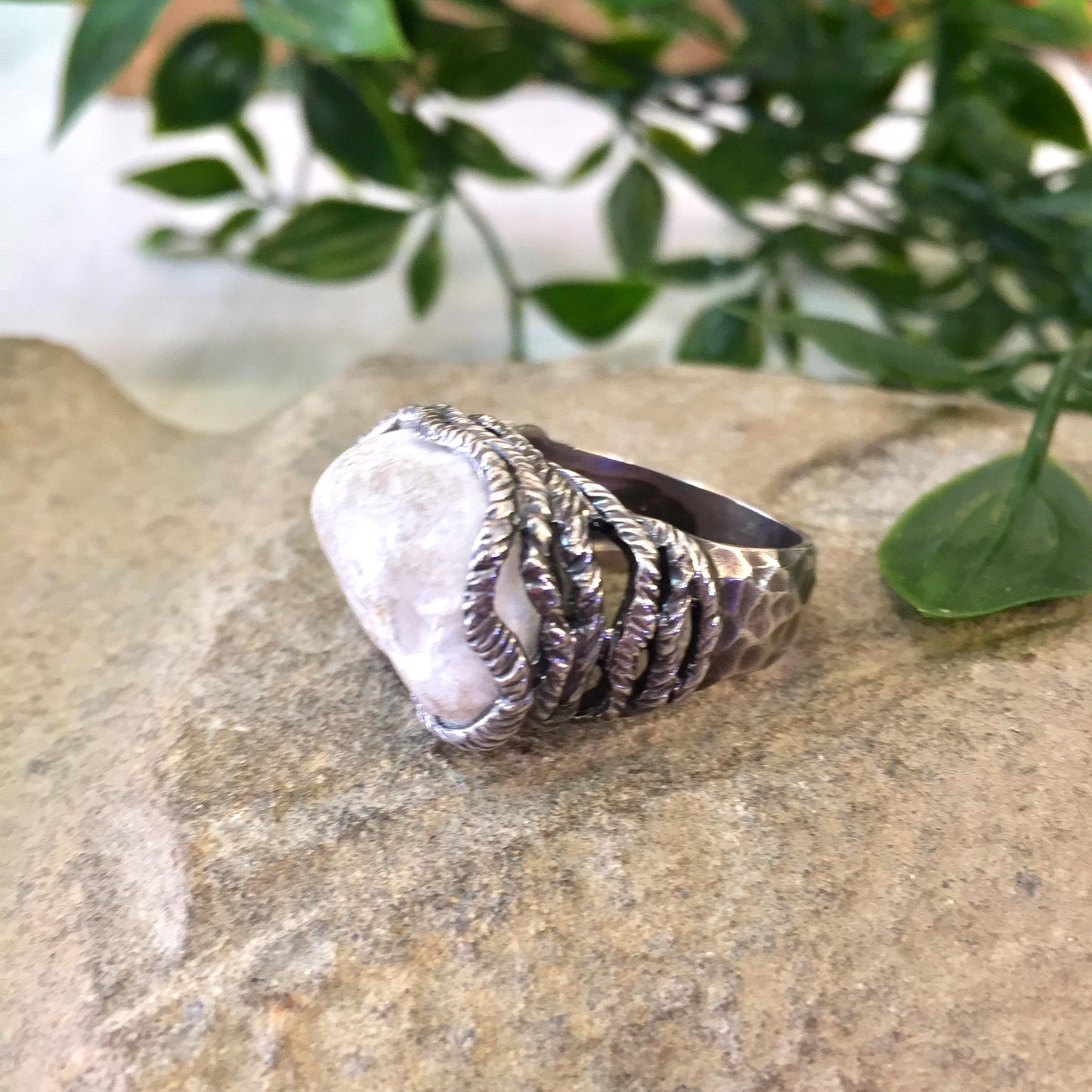 Vintage sterling silver ring with quartz stone featuring hammered texture and rope setting on natural stone background with greenery.