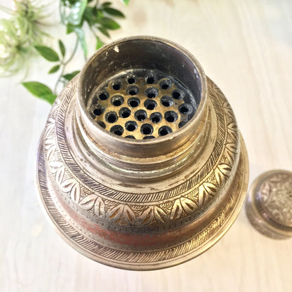 Vintage etched metal cocktail shaker with silver, red and floral design details, featuring perforated strainer top for mixology and serving drinks.