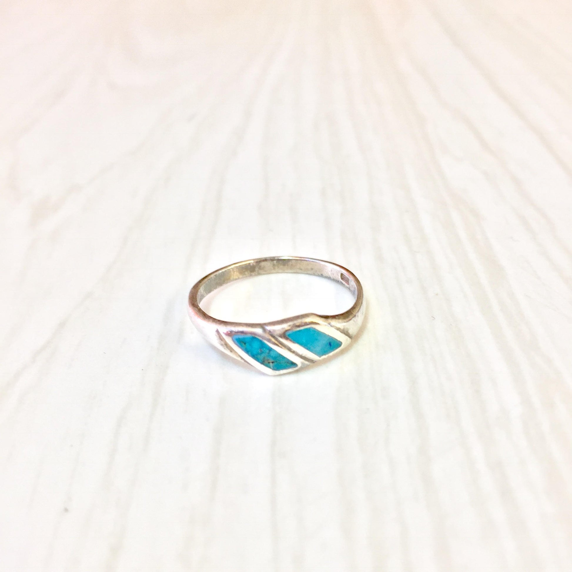 Vintage sterling silver ring with turquoise inlay on textured white background