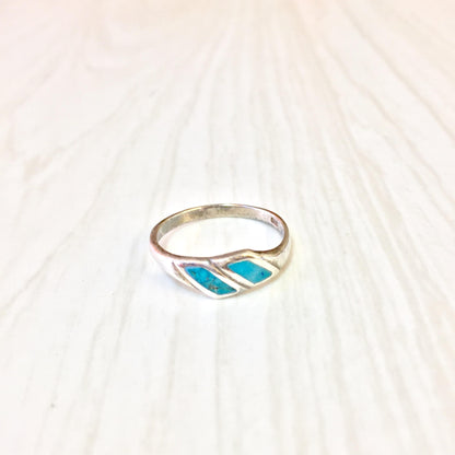 Vintage sterling silver ring with turquoise inlay on textured white background