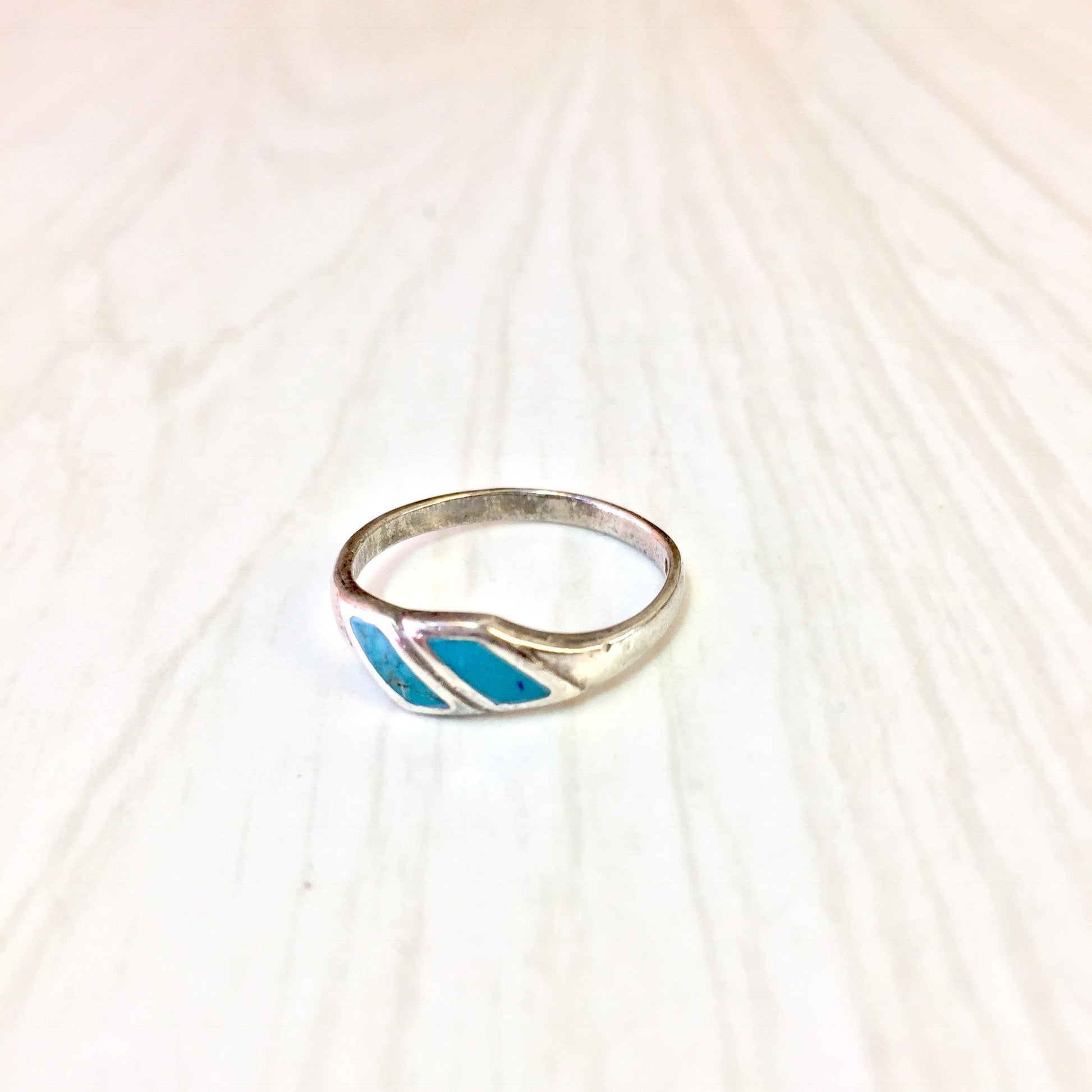 Vintage sterling silver ring with turquoise inlay on textured white background