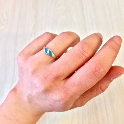 Vintage sterling silver ring with turquoise inlay on a hand against a light wooden background