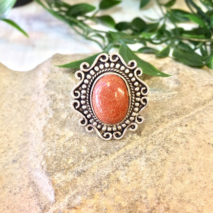 Vintage silver ring with orange druzy quartz and Celtic design on stone surface