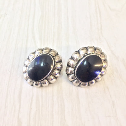 Vintage sterling silver southwestern style clip-on earrings with large black onyx stones set in ornate silver bezels.