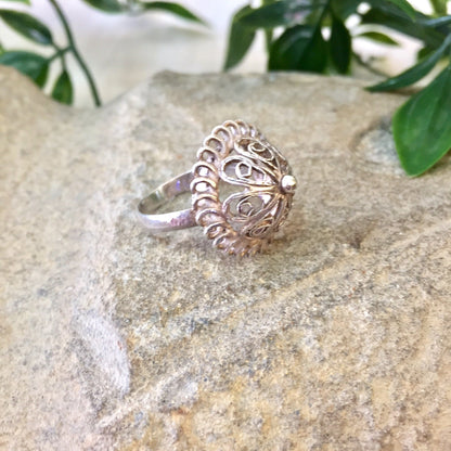 Vintage sterling silver dome ring with intricate cut-out design, placed on stone surface with greenery in background, perfect for weddings or as a Mother's Day gift.