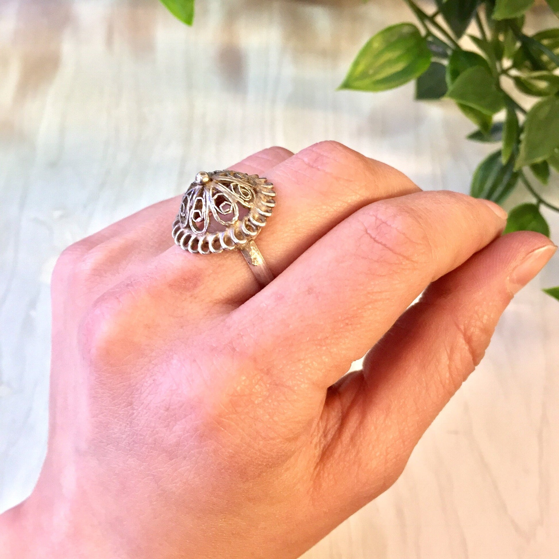 Vintage sterling silver cut-out dome ring on hand next to green plant, perfect gift for mom or wedding jewelry.