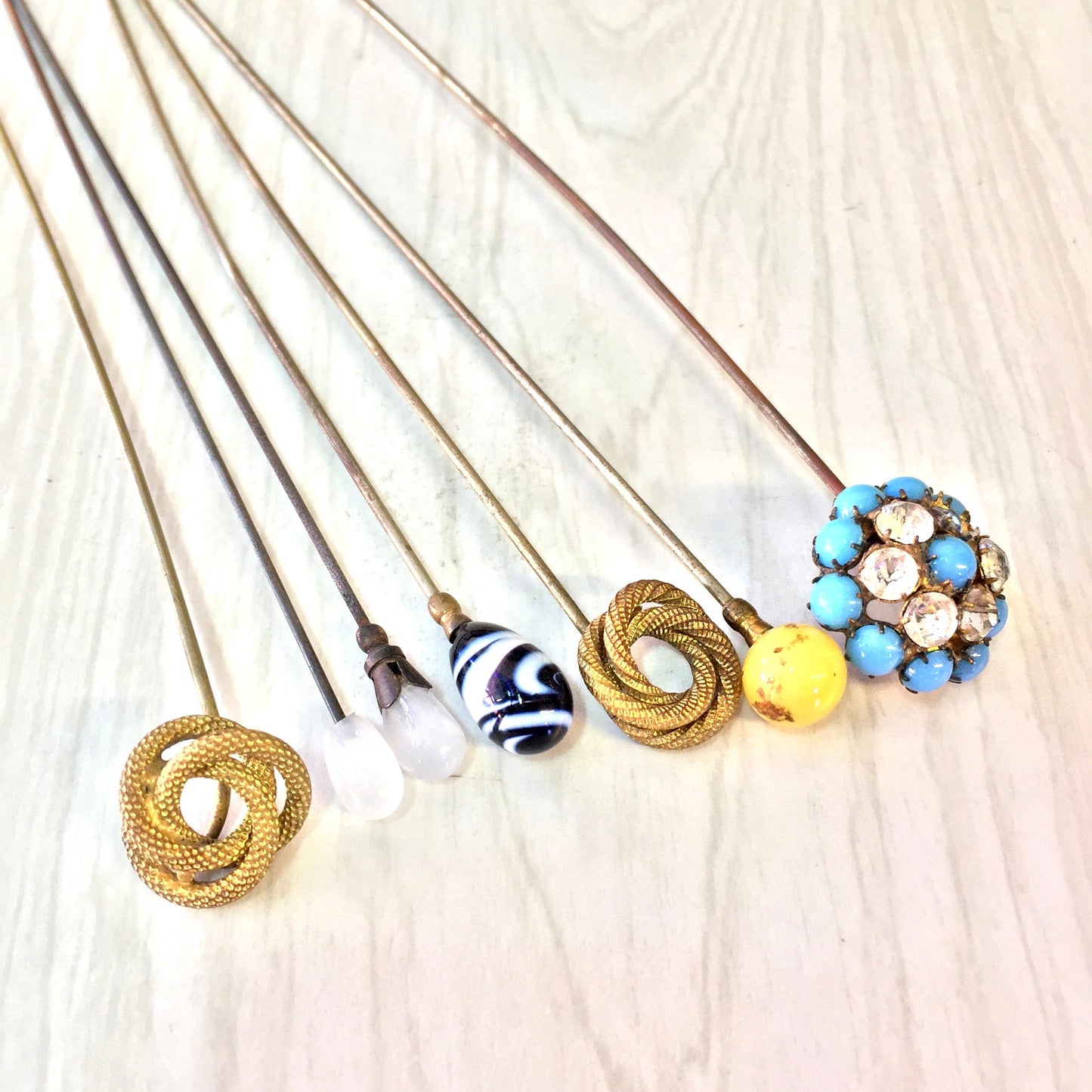 Vintage hat pins in assorted colors and designs, including blue, yellow, black, white and gold. Large decorative stick pins suitable for hats or scarves. Collectible accessories that make a thoughtful gift.