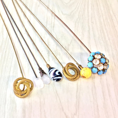 Vintage hat pins in assorted colors and designs, including blue, yellow, black, white and gold. Large decorative stick pins suitable for hats or scarves. Collectible accessories that make a thoughtful gift.