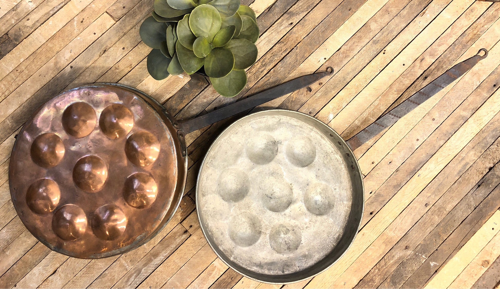 Antique copper poached egg pan and mold on rustic wooden surface with succulent plant