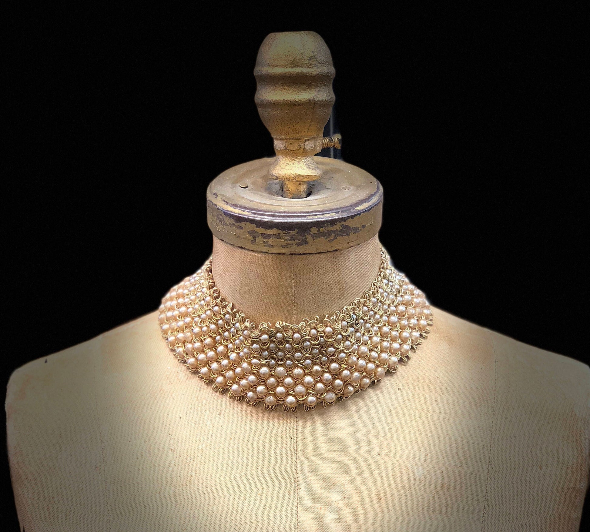 Vintage pearl and bead encrusted collar displayed on a mannequin, showcasing intricate beadwork and design reminiscent of classic fashion eras.
