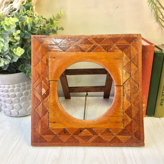Vintage wooden picture frame with geometric triangle inlay design, standing on table with potted plant in background, suitable as vintage home decor or handmade gift.