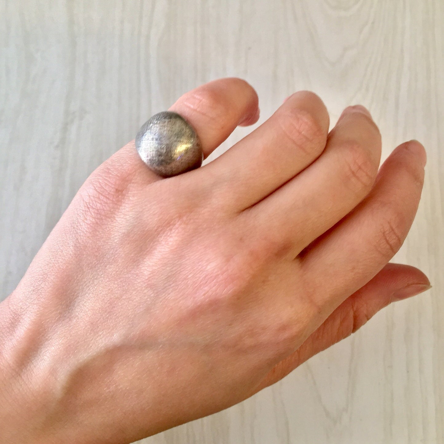 Vintage silver pinky ring held in hand, showing textured sterling silver surface and small size suitable for a pinky finger or statement jewelry gift.