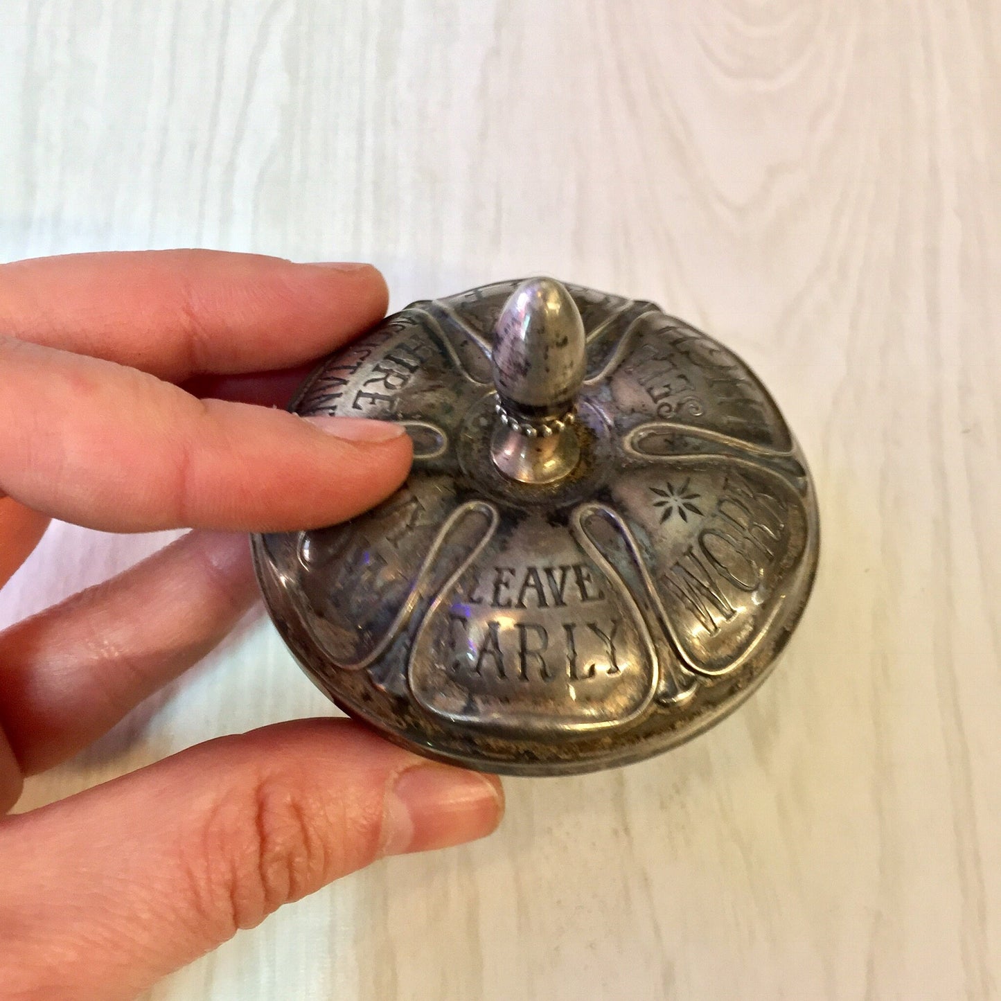 Antique Gorham sterling silver and ebony spinning top toy engraved with "I Rave Man", held in hand to show detail and scale.