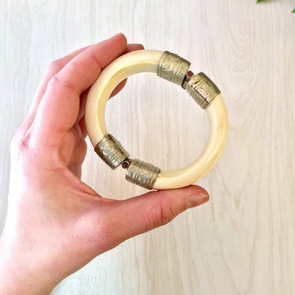 Vintage white and silver hinged bangle bracelet held in hand, showing pin closure