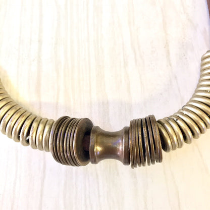 Vintage brass coil choker necklace on wooden surface