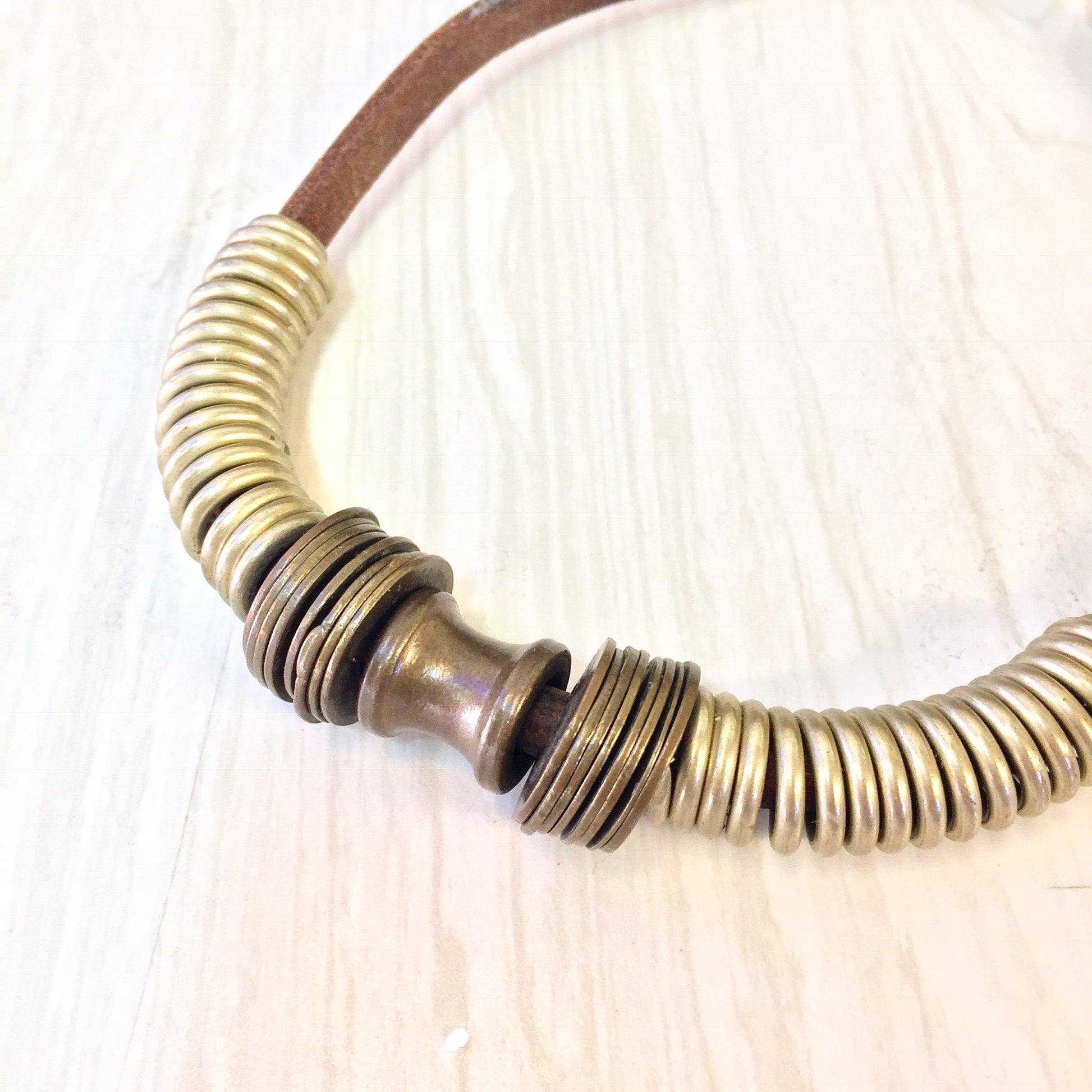 Vintage brass coil choker necklace on leather cord, close-up view on wooden surface