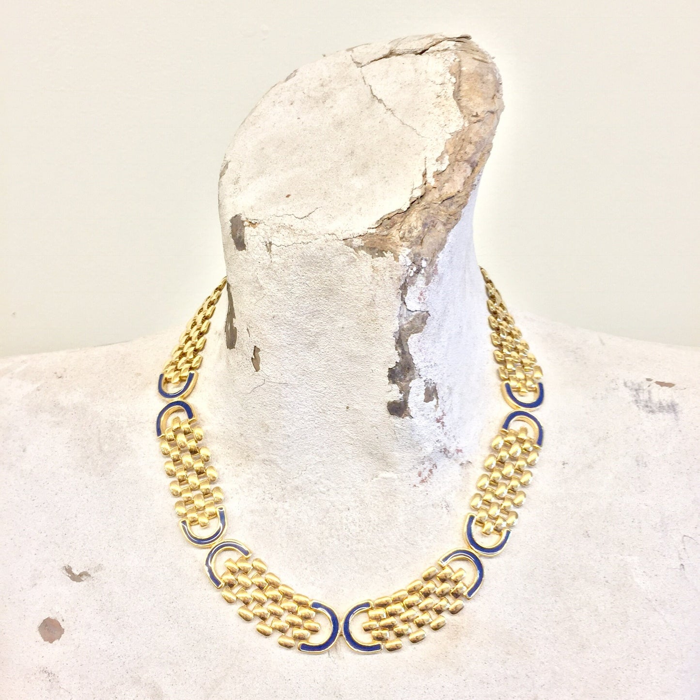 Vintage gold tone chain link statement necklace with dark blue accents, displayed on white rock - elegant gift idea for mom or unique vintage jewelry piece.