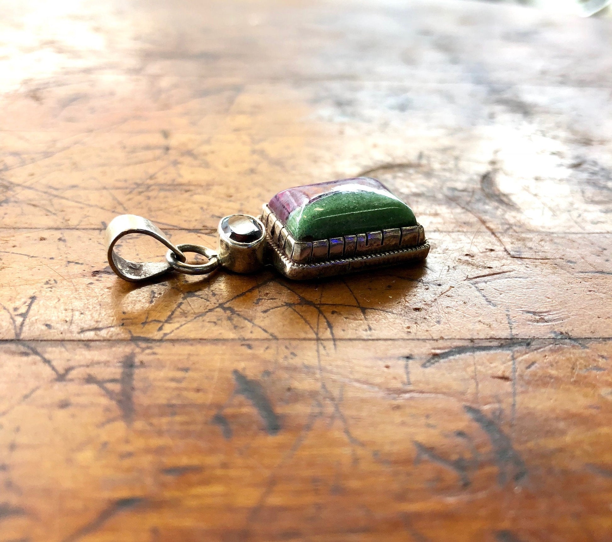 Vintage sterling silver and gemstone pendant on antique wooden surface