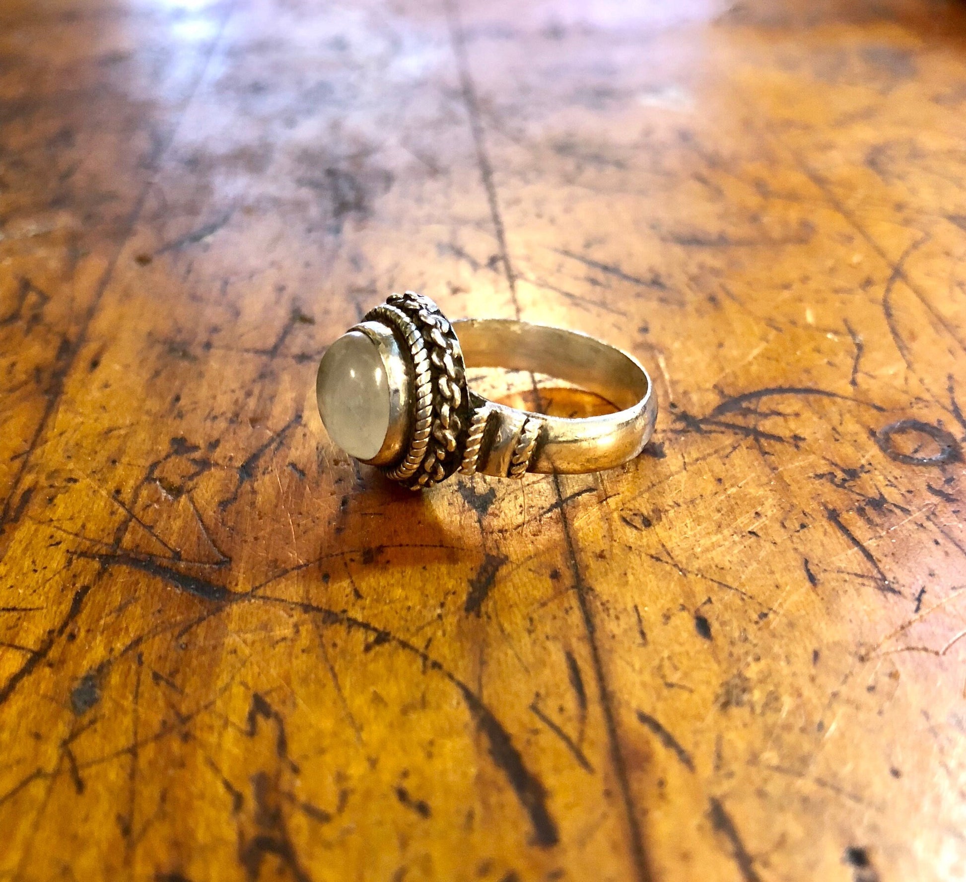 Vintage sterling silver moonstone ring with iridescent white stone on scratched wooden surface