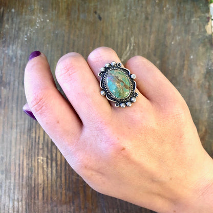 Vintage sterling silver ring with blue Royston turquoise cabochon stone, worn on hand against rustic wooden background