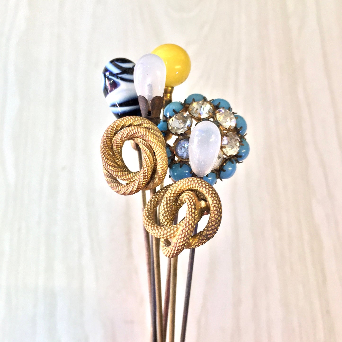 Vintage gold hat pins with decorative blue, yellow, black and white beads arranged in a bouquet, collectible gift idea for mom or fashion accessory enthusiast