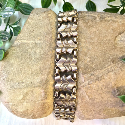 Vintage silver tone link bracelet on stone background with greenery