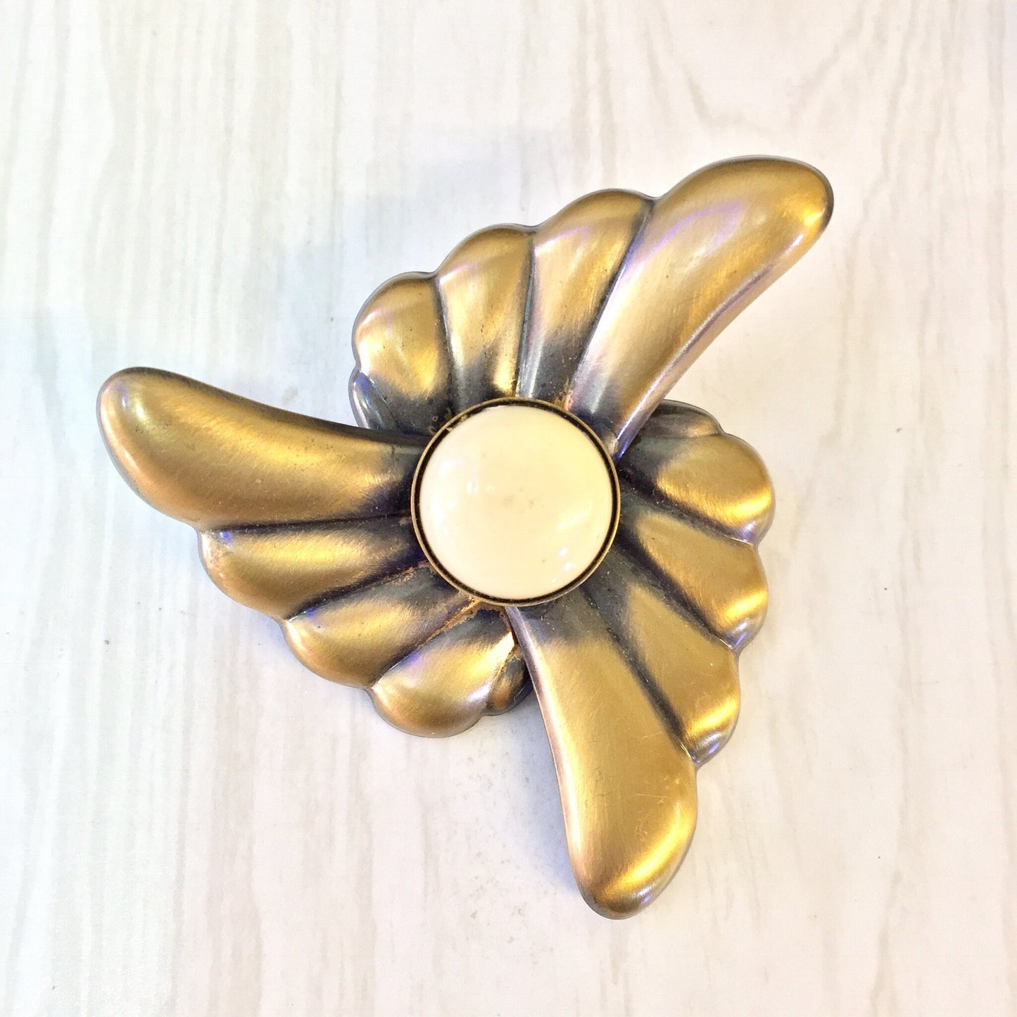 Vintage gold flower clip-on earrings with white center on light wood background