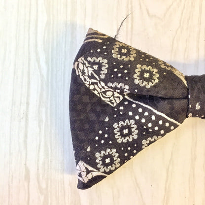 Vintage black bow tie with floral pattern, clip-on style, suitable as a gift for Dad or Father's Day, close-up view on wooden surface.