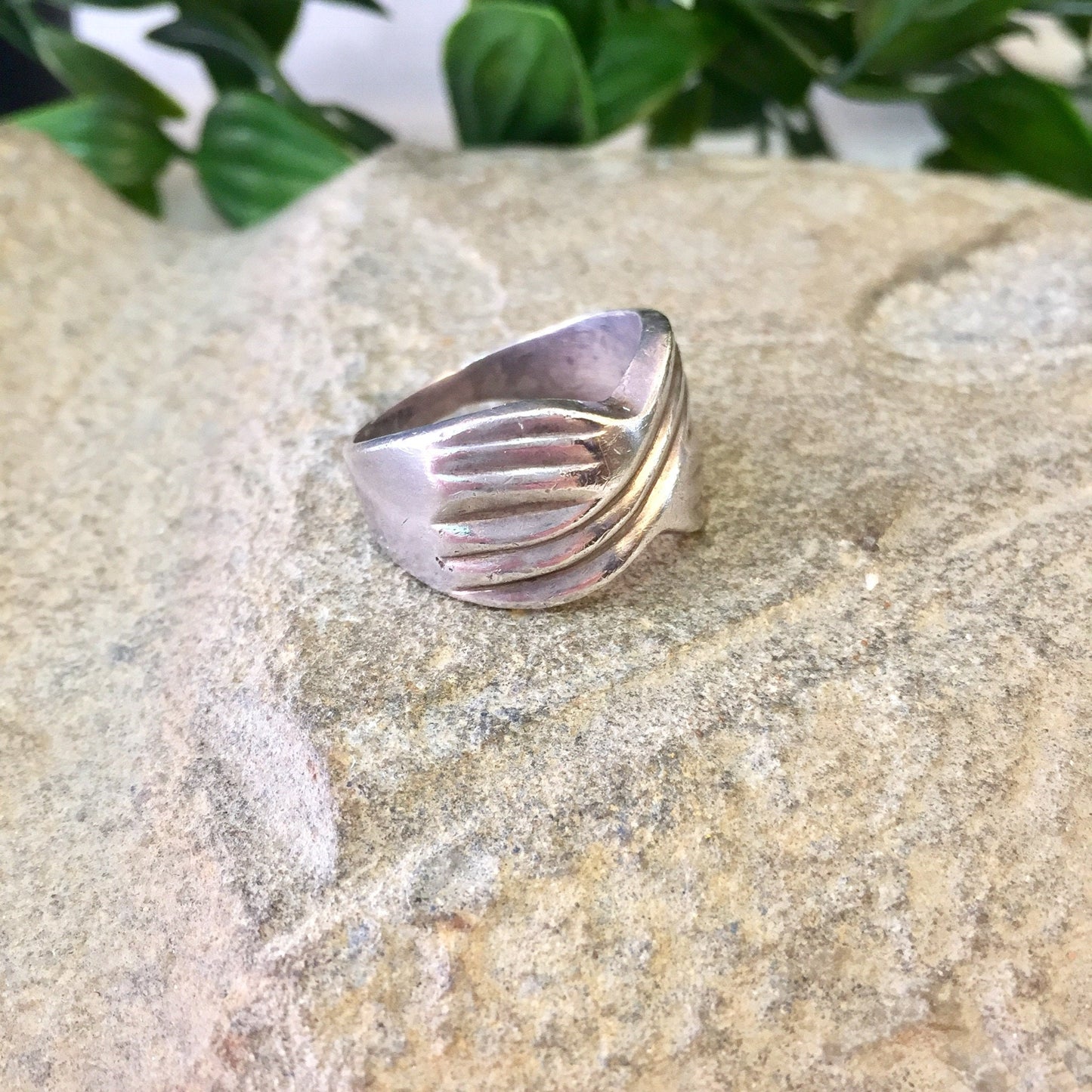 Vintage sterling silver band ring with X design, statement jewelry gift for Mom or Mother's Day, displayed on stone surface with greenery in background.