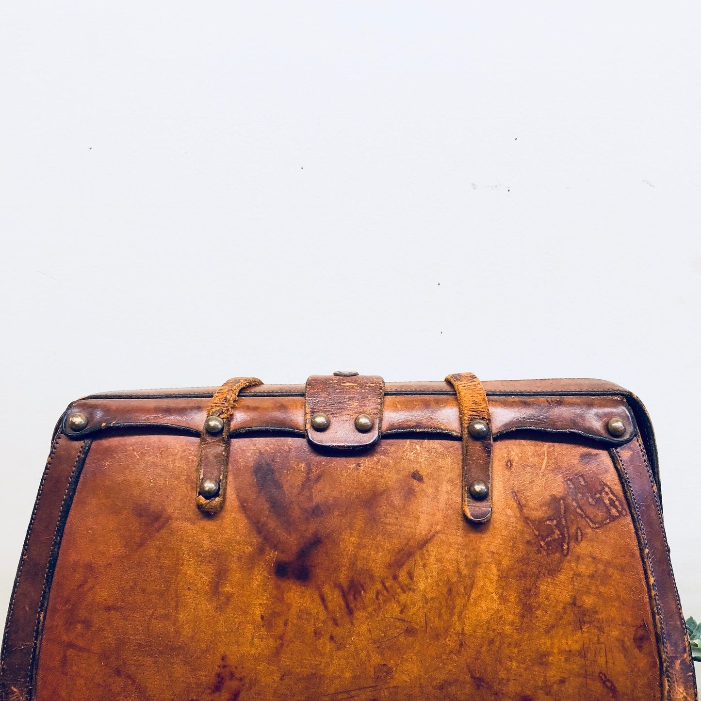 Vintage brown leather handbag with rustic, bohemian style from the 1960s, featuring buckle straps and a well-worn patina