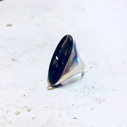 Vintage sterling silver ring with elongated black onyx gemstone setting on white concrete background