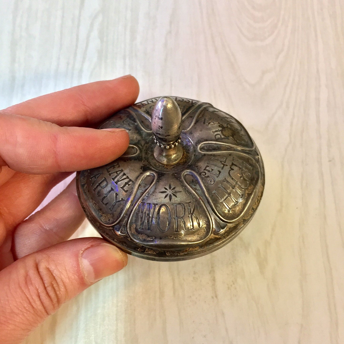 Antique sterling silver and ebony spinning top toy by Gorham featuring astrological symbols and fortunes, held in hand against wooden background